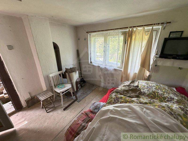 Interior of a family house with a bed, chair, table, and a small television.