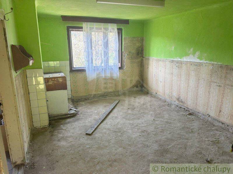An empty interior in a family house with a view through the window, green walls, dirty floor.