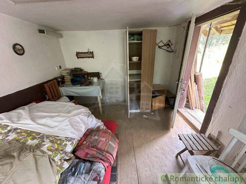 A room in a family house with a bed, a table, a wardrobe, and books on the table.