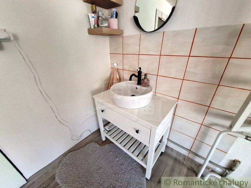 A small bathroom in a family house with a sink, mirror, and shelves.