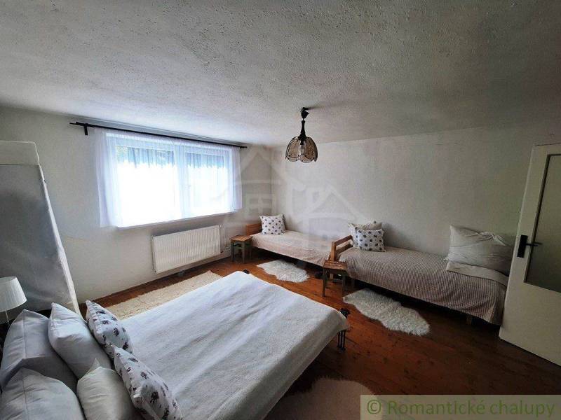 A bedroom in a family house with three beds and a wooden floor.