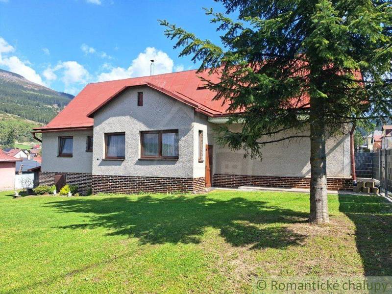 A family house in Telgárt with a red roof and a grassy garden, with a landscape in the background.
