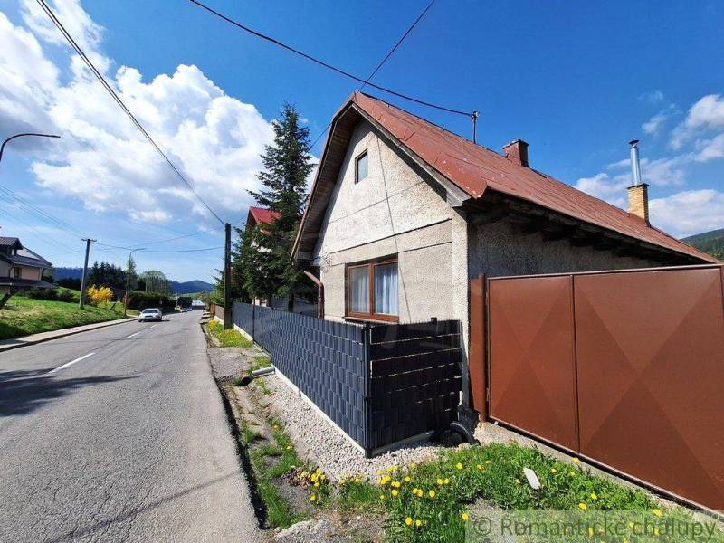 A family house in Telgárt with a wooden fence, blue sky, and a road.