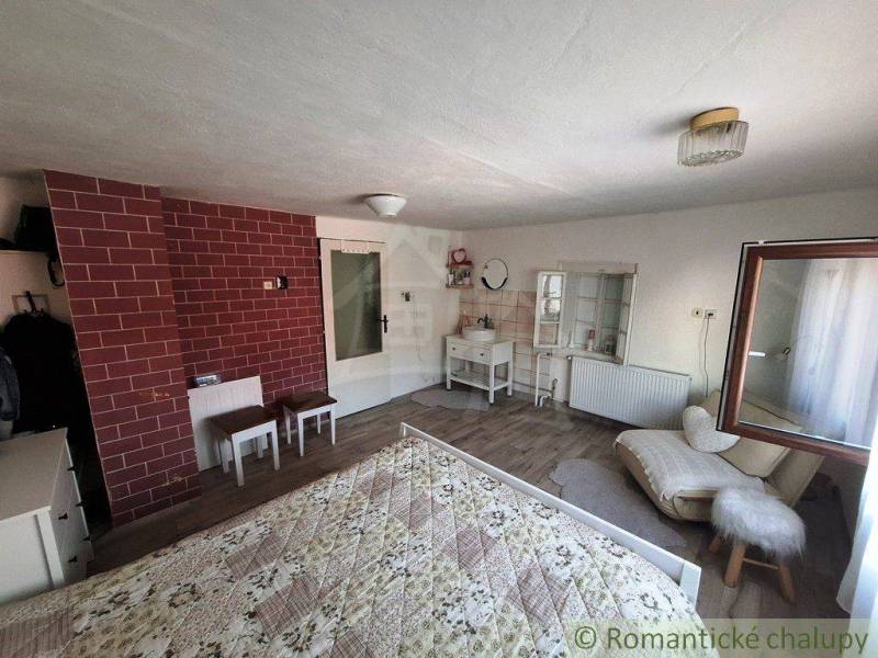 A room with white furniture, an exposed brick wall, and a comfortable bed in a family house.