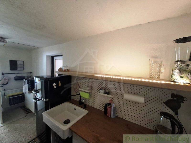 A kitchen in a family house with a wooden countertop and a black refrigerator.