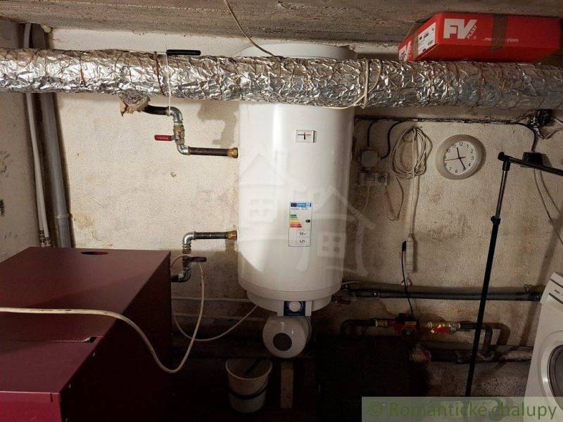The boiler room of a family house in Telgárt contains a water heater and piping.