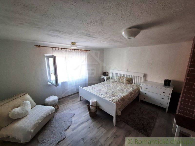 A bedroom in a family house with white furniture, a comfortable sofa, and wooden flooring.