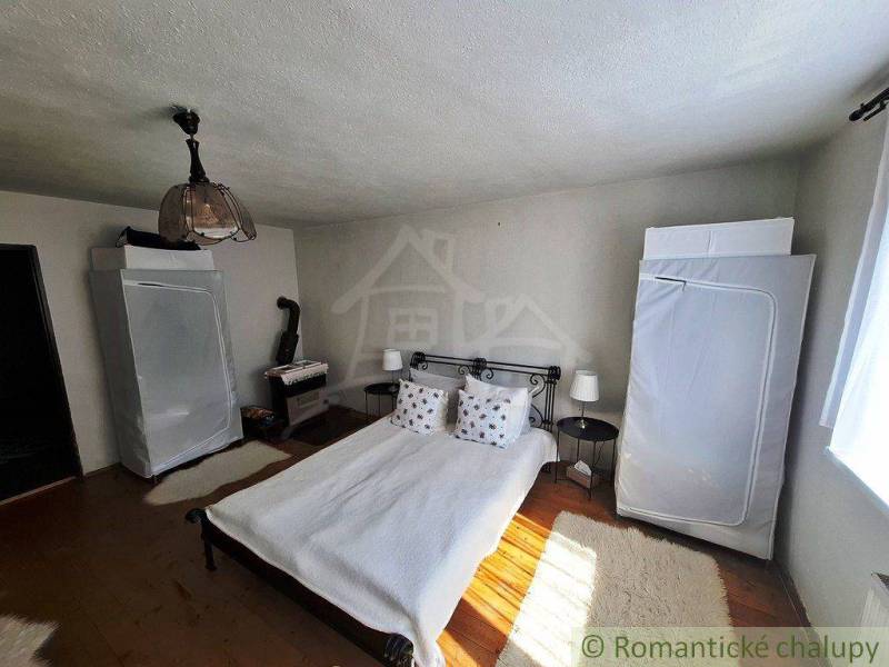 A bedroom in a family house with a metal bed and a wood stove.