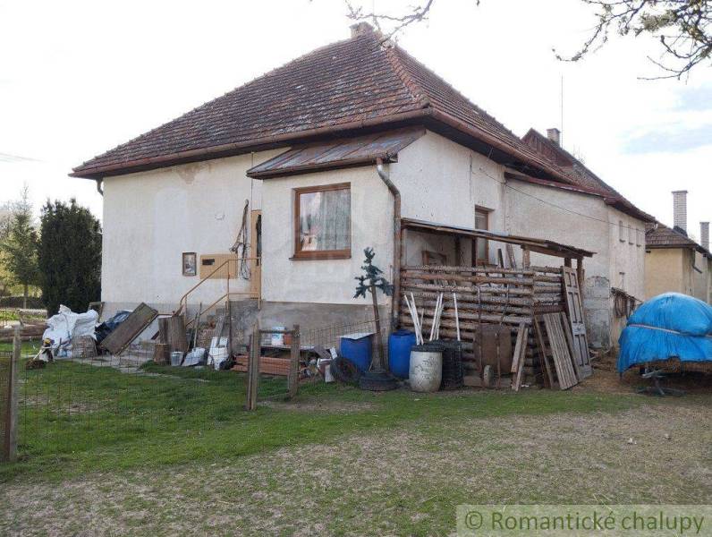 A rural family house, stored wood, and tools in the garden complement the traditional atmosphere.