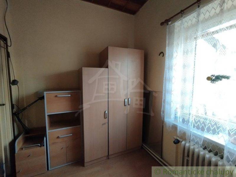 A room in a family house with simple furniture, white curtain, light from the window.