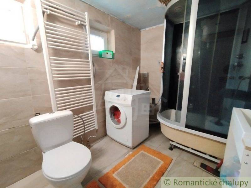 Bathroom with a washing machine and shower, part of a family house, equipment includes a toilet and a ladder radiator.