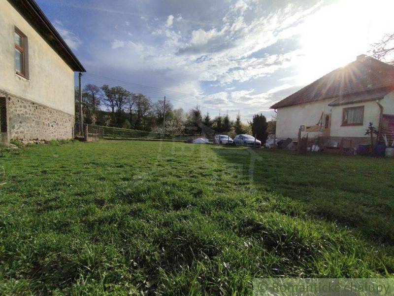 A grassy plot between family houses, cars parked in the back, sunny day.