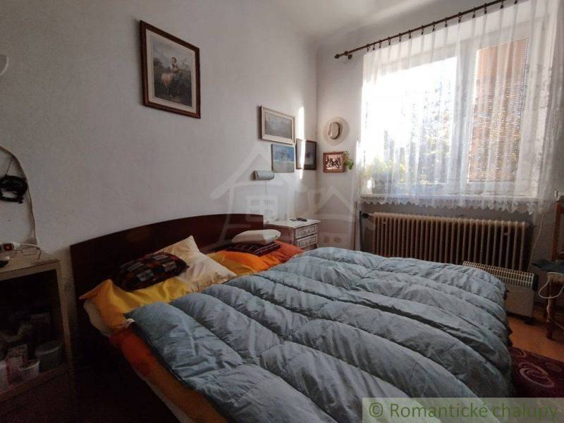 Bedroom with paintings, decorations, a window, and a bed in a family house. A romantically coordinated space.