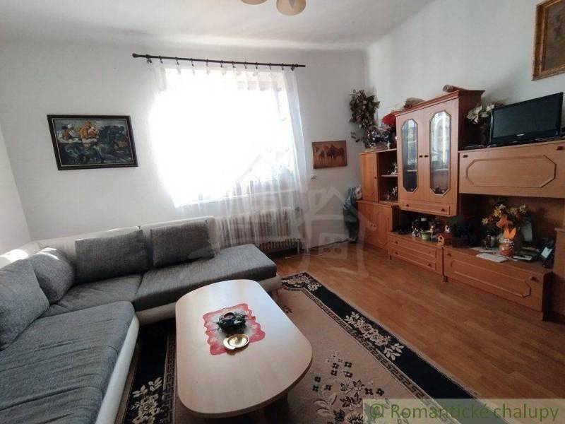 Living room in a family house with a corner sofa, wooden wall unit, and hall decoration.
