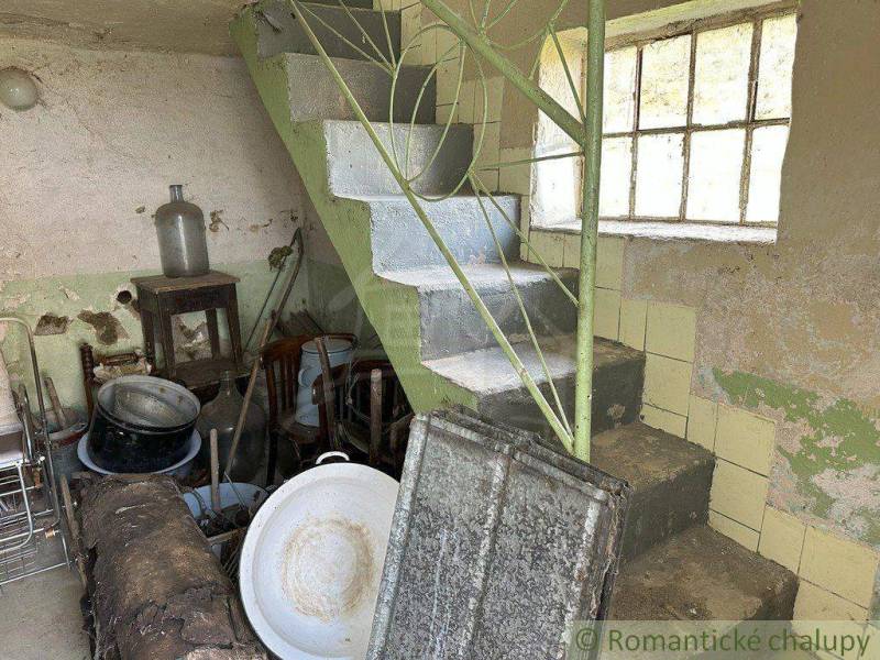 An old cellar with a staircase, a window, and a lot of unnecessary items evokes the image of a family house.
