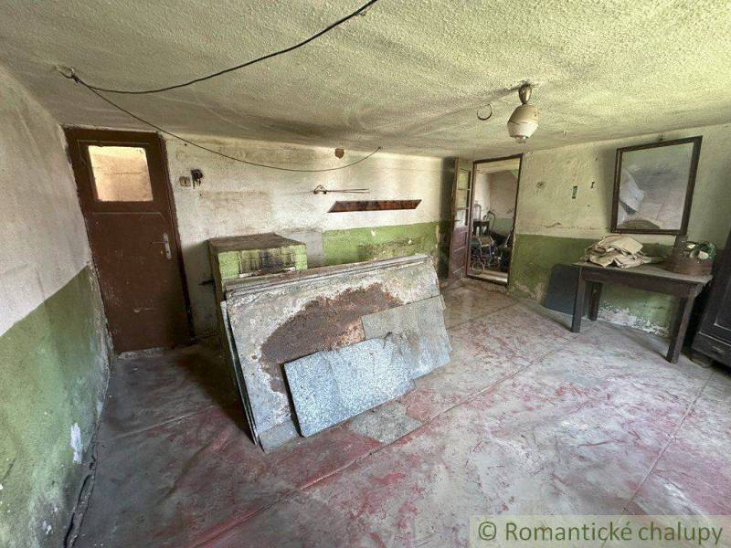 An old cottage interior with a table next to a mirror and a door to another room.