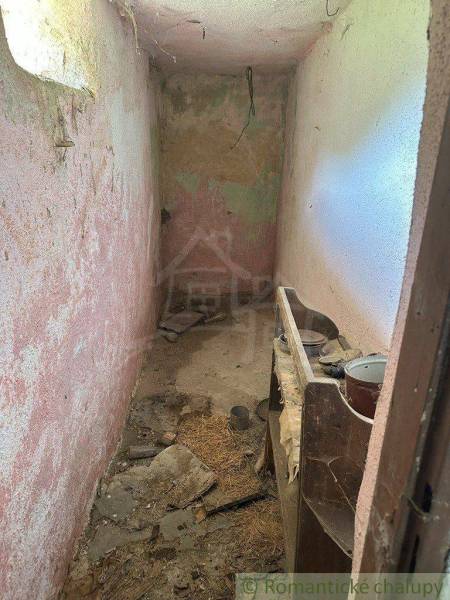 Abandoned narrow room with peeling plaster and broken floor in a family house.