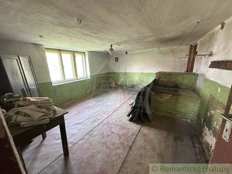 Abandoned room in a family house, green walls, wooden furniture, old stone stove.