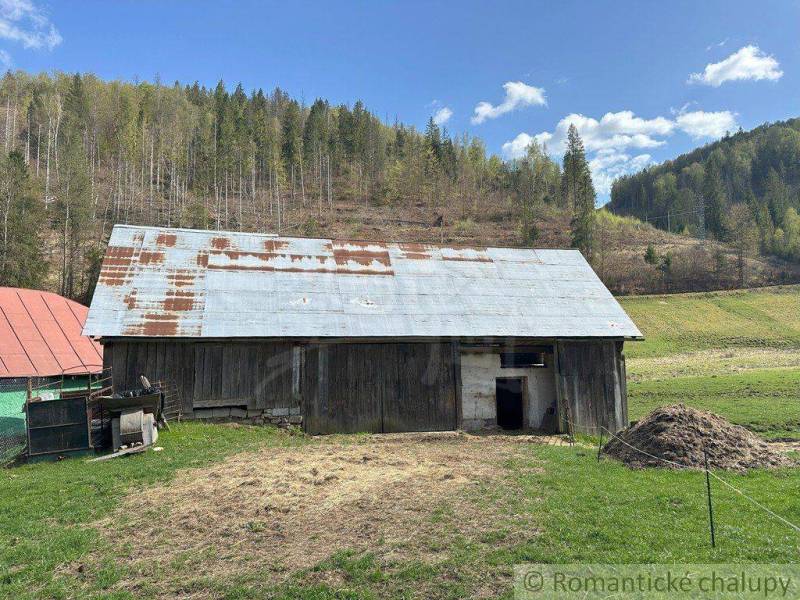 An old barn with a tin roof in a mountainous landscape. Rustic atmosphere and a family house.