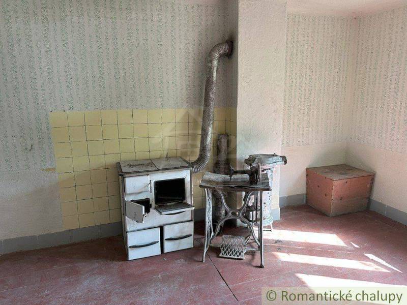Traditional family house with a vintage stove, old table, and a wooden storage cabinet.
