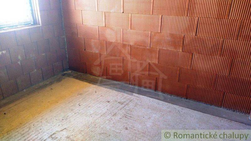 A construction site with a brick wall and a window, part of a family house under construction.