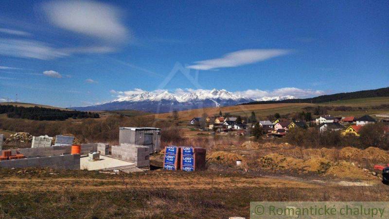 Building plot with a beautiful view of the mountains and a partially constructed family house in nature.