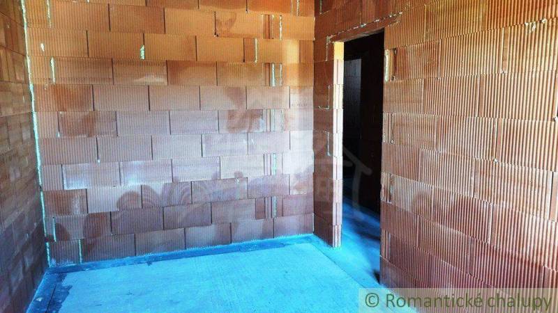 A family house under construction with unplastered brick walls and an open door space.