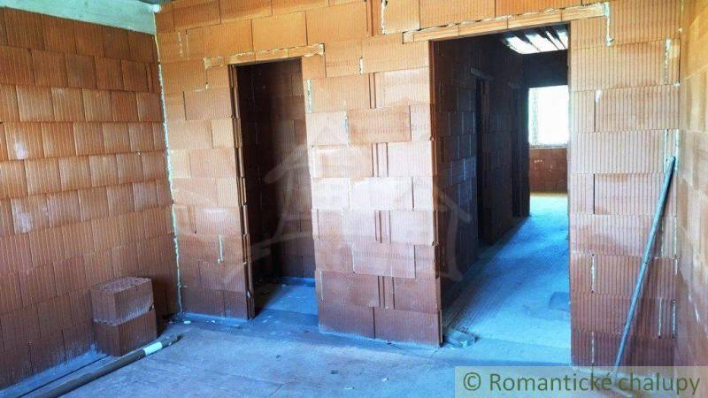 The shell construction of a family house, rooms with unplastered bricks, windows letting in light.