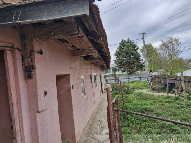 An older family house with a yard, garden, and fencing in the countryside.