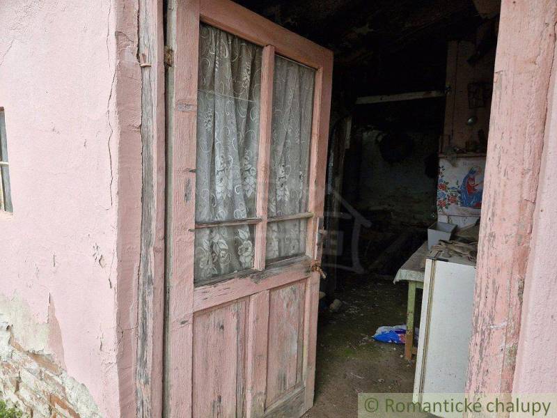 Old wooden door with a lace curtain leading into a neglected interior of a family house.