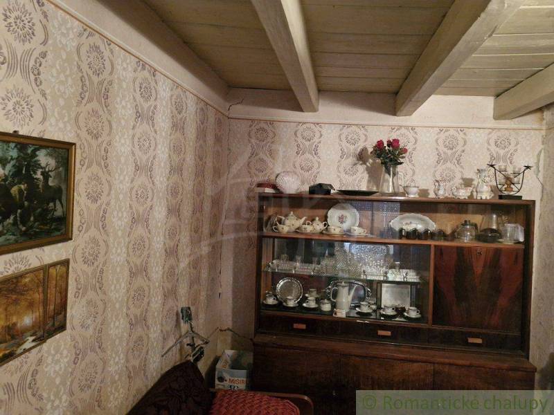 A visible rustic living room in a family house with a display cabinet full of antique glass and porcelain.