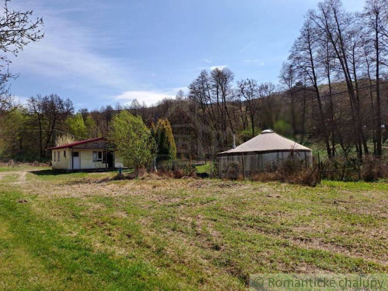 In the photo, there is a cottage in a natural setting with a clear blue sky.