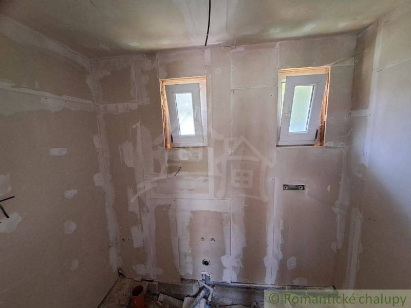 A construction room with two windows, basic structure for a cottage.