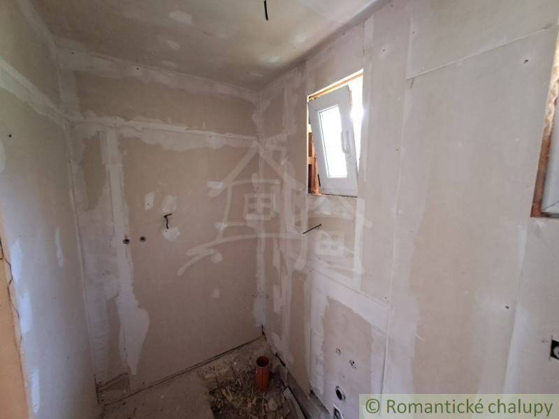 A construction room under renovation with a window, suitable for remodeling in a cottage.