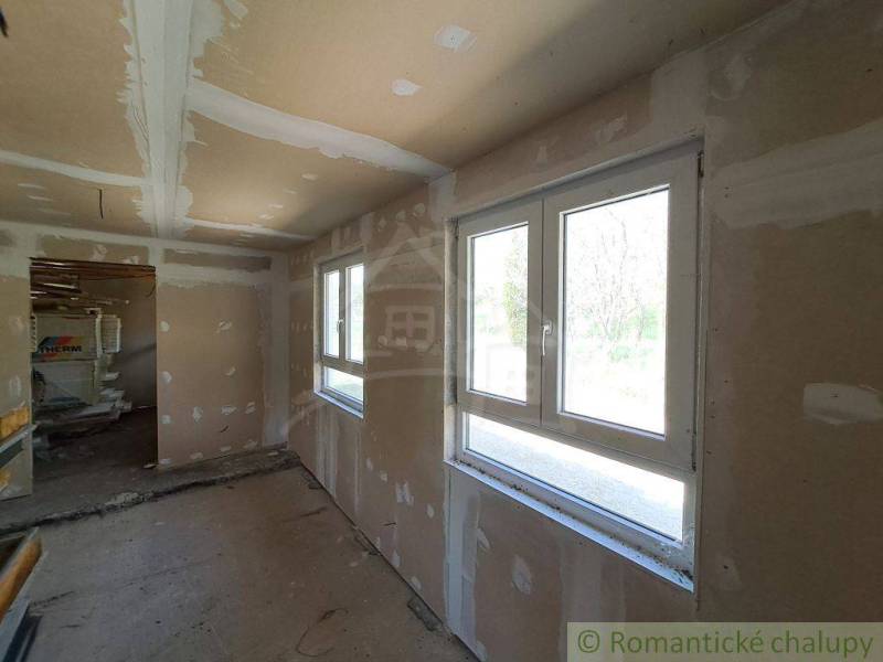 Interior in a cabin with unfinished walls and large windows, waiting to be completed.