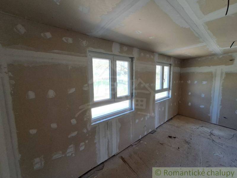 Unfurnished room and windows in a cottage under renovation with a view of the garden.