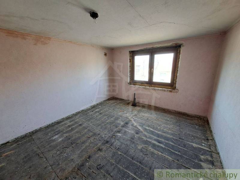 An empty room with a wooden floor, a plastic window, and a family house.
