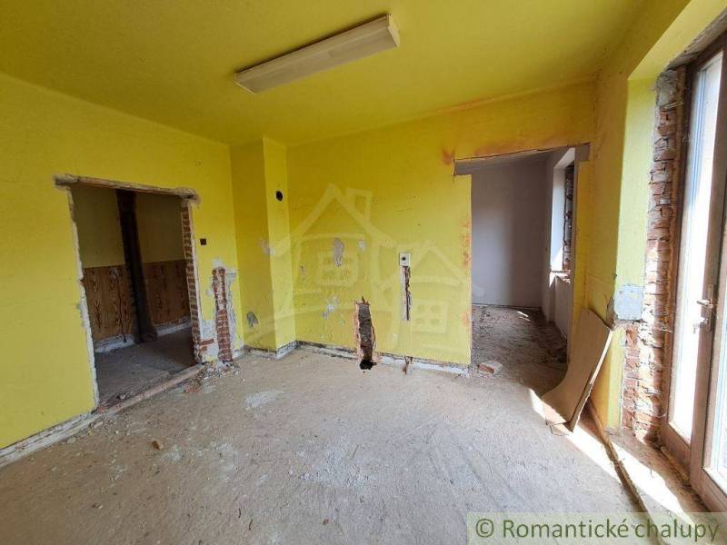 A room in a family house with exposed bricks and yellow walls, awaiting renovation.
