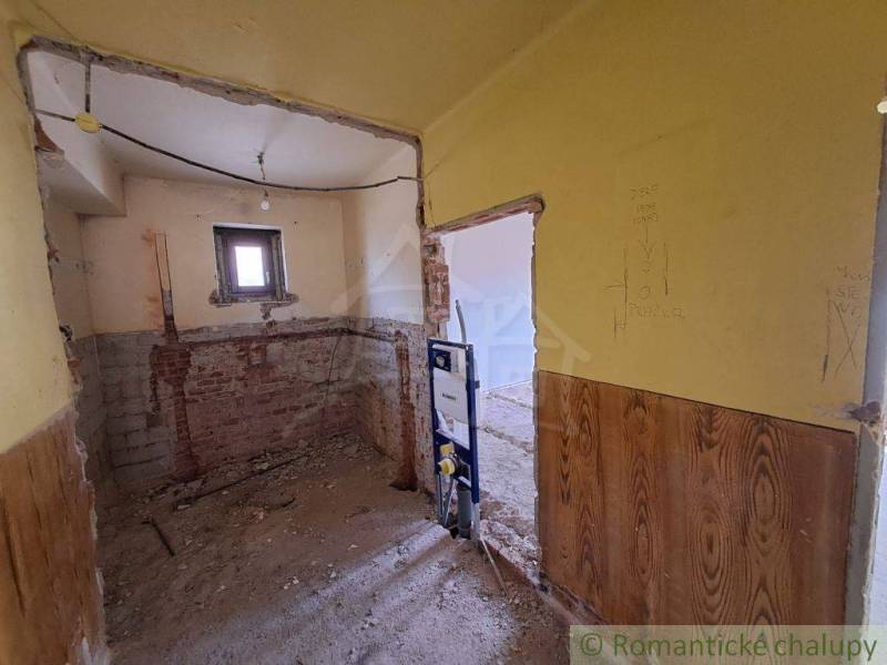 An unfinished bathroom in a family house with exposed brick walls awaits renovation.