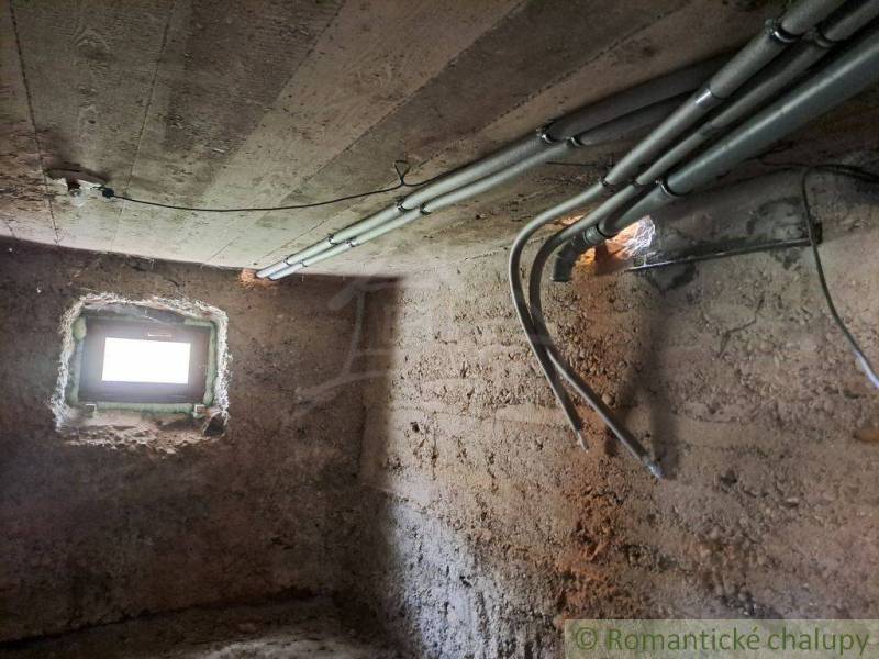 Basement of a family house with a window and electricity; rough plaster, concrete ceiling.