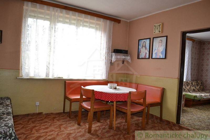 Interior of a family house with a dining nook, armchairs, curtains, pictures on the wall.