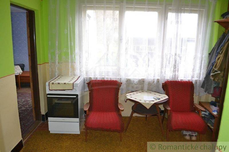 Living room in a family house with red armchairs, a table, and a retro stove.