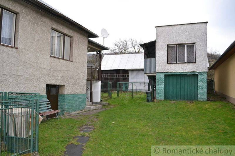 Family house with a garage and yard, buildings, fence, and green lawn.