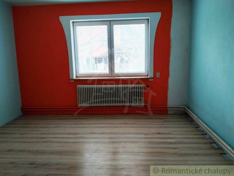 A room in a family house with a colorful wall, a lamp, and a wooden floor.