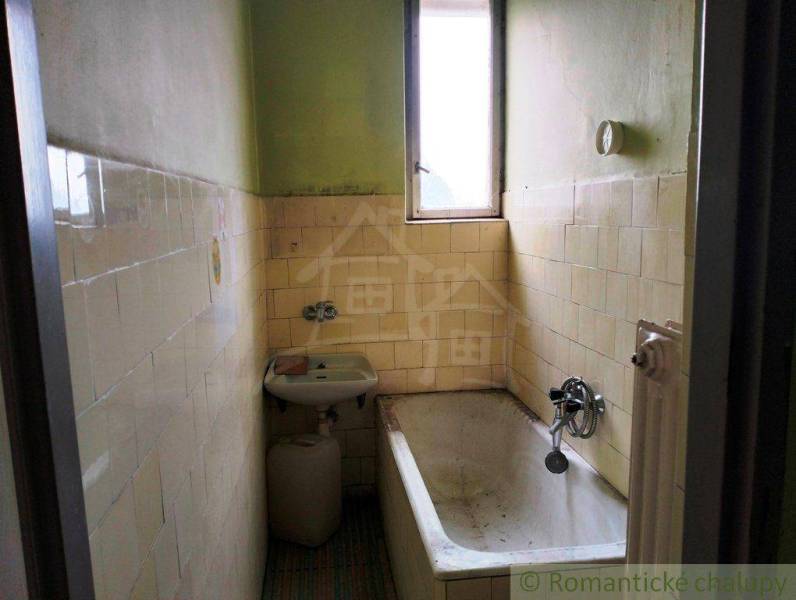 Narrow bathroom with a bathtub and a sink in a family house, typical rural environment.