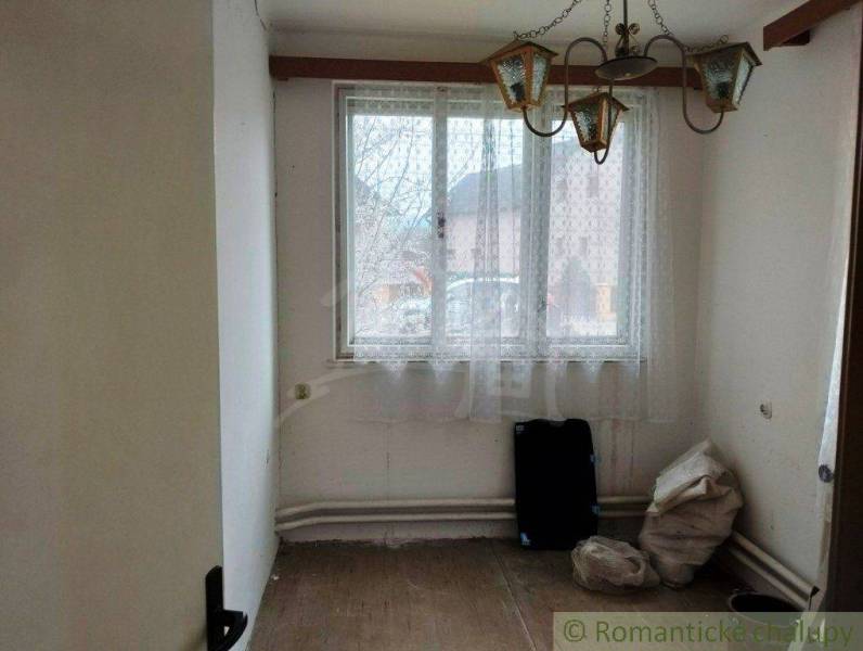 Empty room in a family house with a chandelier, window, and natural lighting.