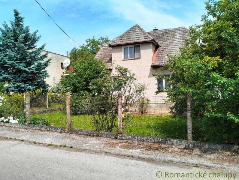 A family house in Košeca surrounded by greenery and a fence on a quiet street.
