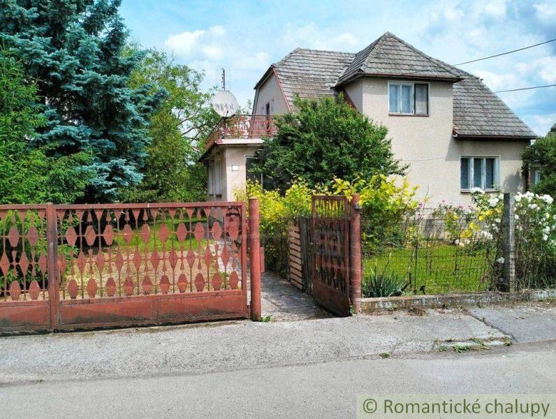 A family house in Košeca with a flower garden and a wooden gate in front of the house.