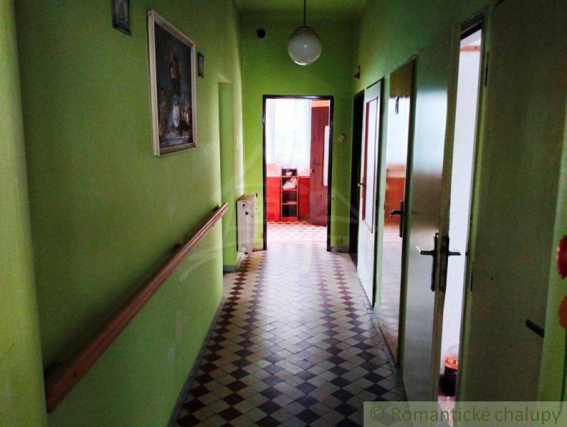 Green hallway in a family house with tiles and doors on the sides.