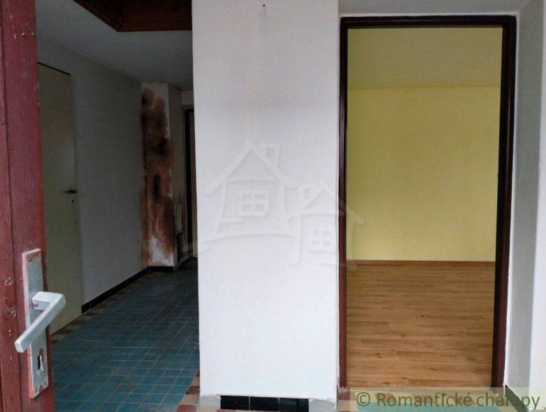 Entrance to a family house with a bright room, wooden floor, and tiles.